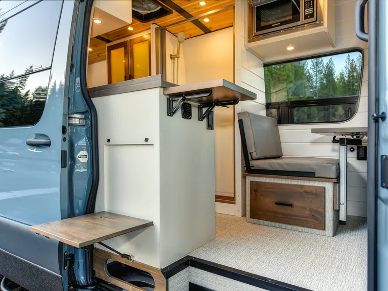 Open campervan door revealing a cream and wood interior